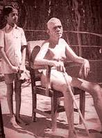 V. Ganesan standing behind Ramana Maharshi in the 1940s.